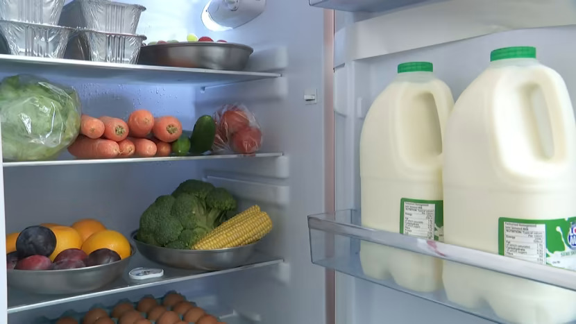 An image of an open fridge showing fruit and vegetables inside.