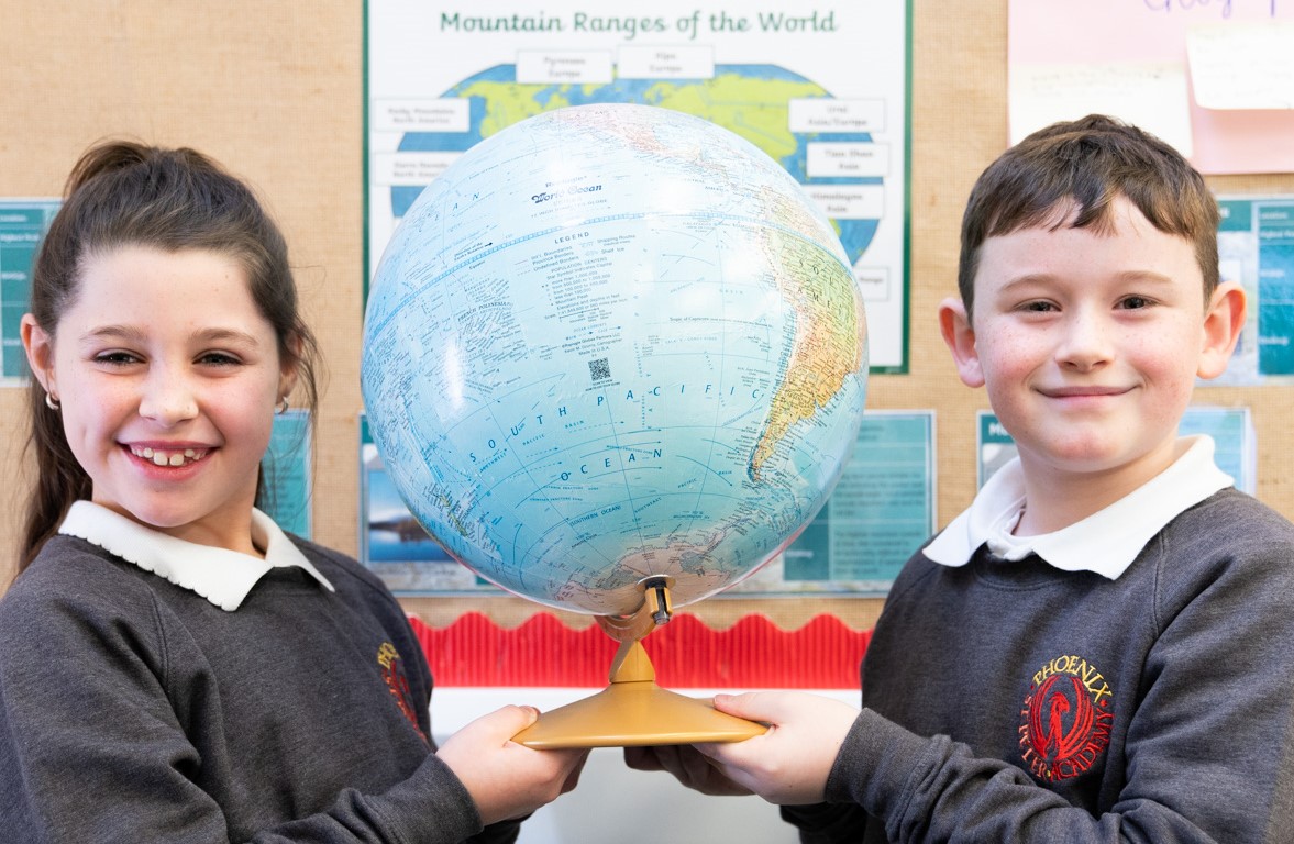 A picture of two children holding a Globe in a classroom.