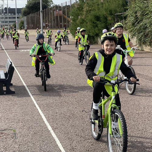 A picture of a child in high visibility clothing cycling on their bike on a cycling path.